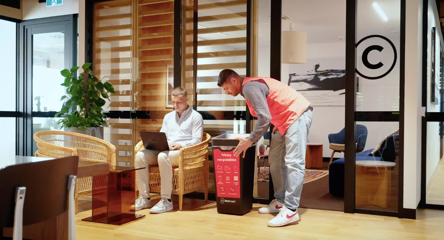 ReSmart team member dropping items into a ReSmart tricky recyclables bin in an office