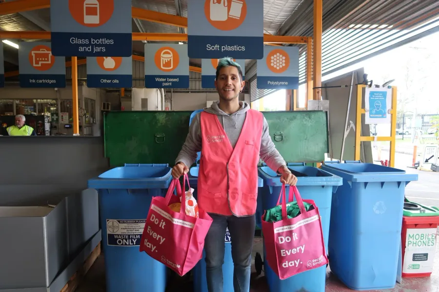 ReSmart team member holding pink bags in front of sorting bins
